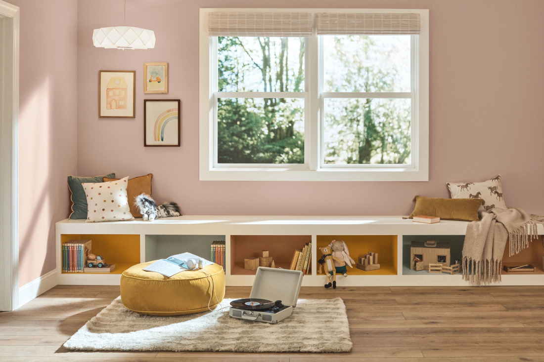 A sunny indoor children’s playroom with built-in bench. Walls are painted neutral mauve mystery.
